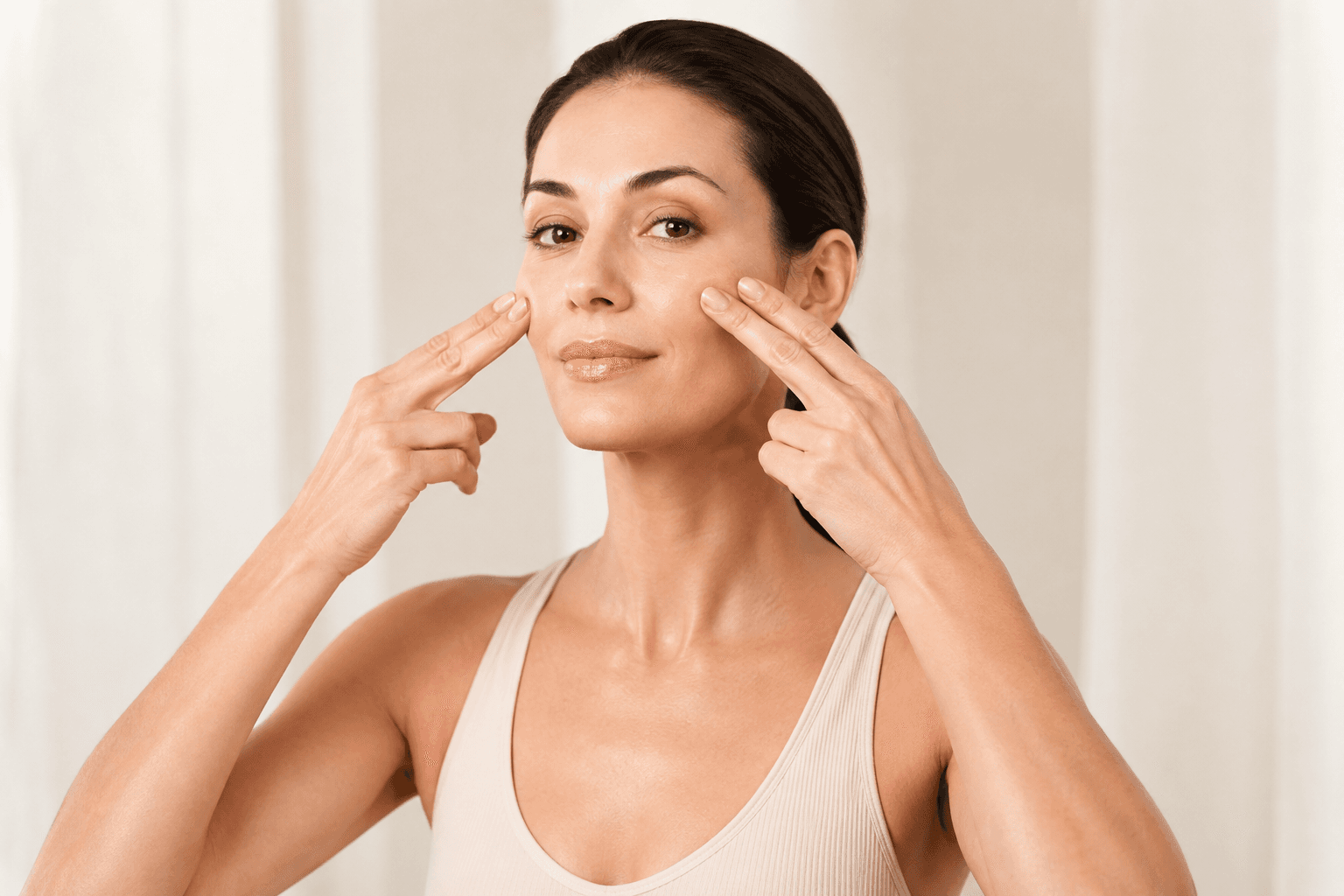 A woman demonstrating a gentle movement along her cheeks